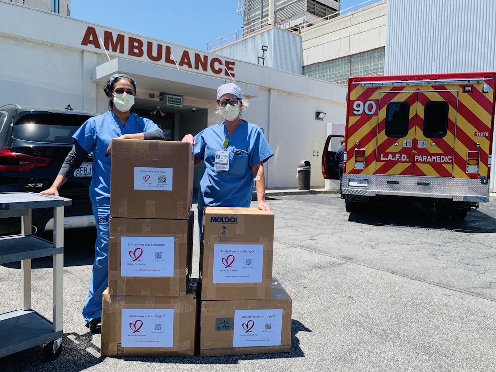 Hombre con polo azul de pie junto a cajas de cartón marrón