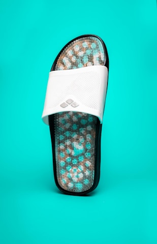 Close-up of a hand holding a soft, cushioned Sponch sandal amid natural light.