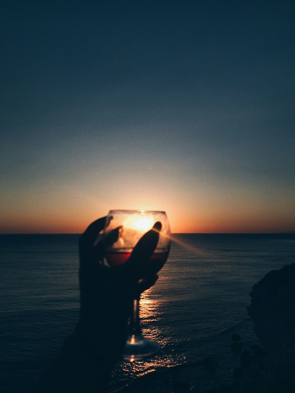 silhouette of person holding glass of water during sunset