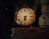 A vintage ornate clock with golden accents displayed on a wooden shelf.