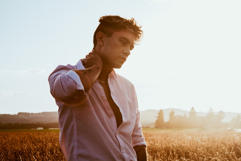 man in white dress shirt standing on brown grass field during daytime