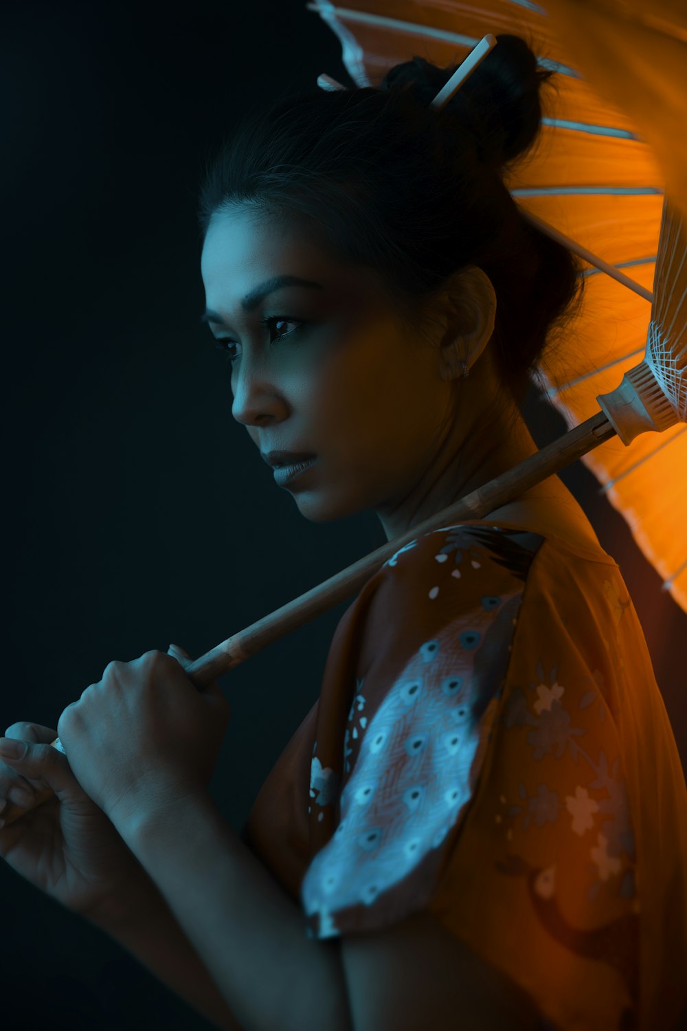 woman in orange and white floral dress holding umbrella