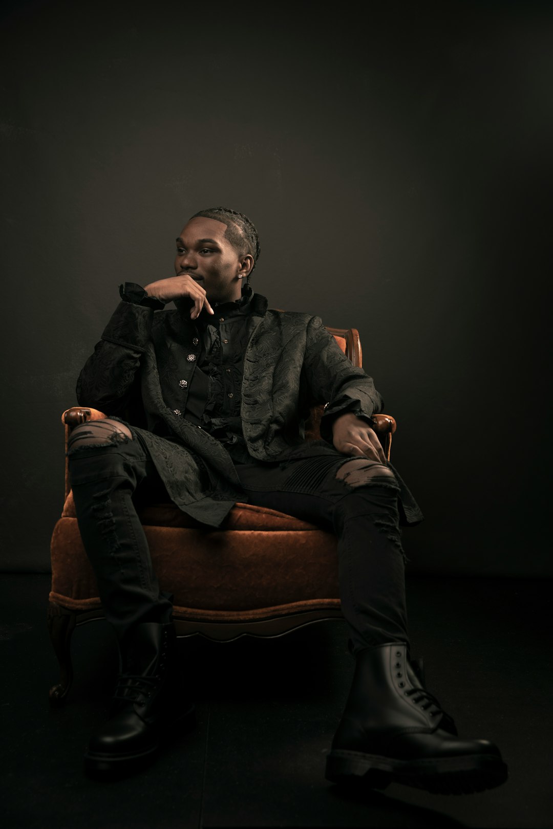 man in black jacket sitting on brown sofa chair