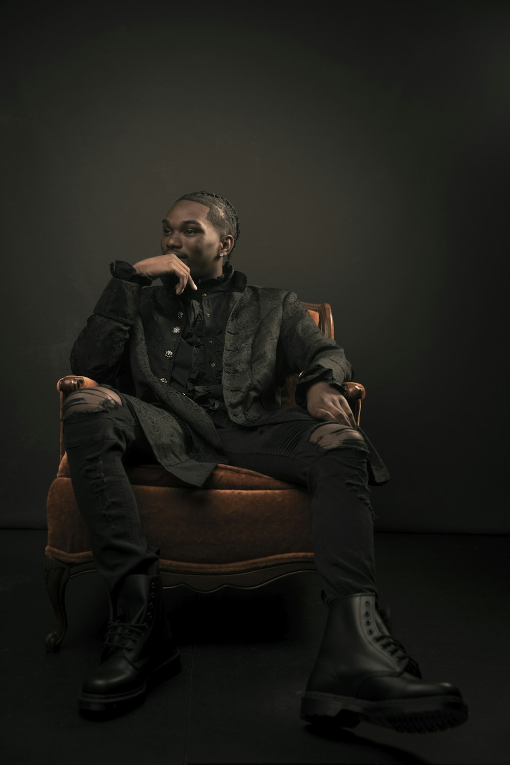 man in black jacket sitting on brown sofa chair