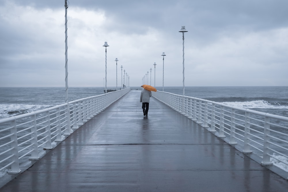 person in black jacket walking on bridge during daytime