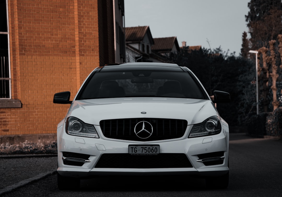 white mercedes benz c class parked near brown brick building during daytime