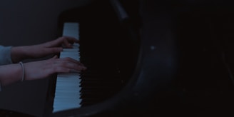 Close-up of hands pressing piano keys in a bright music classroom