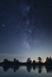 The Southern Cross constellation shining brightly over a calm lake reflecting the night sky