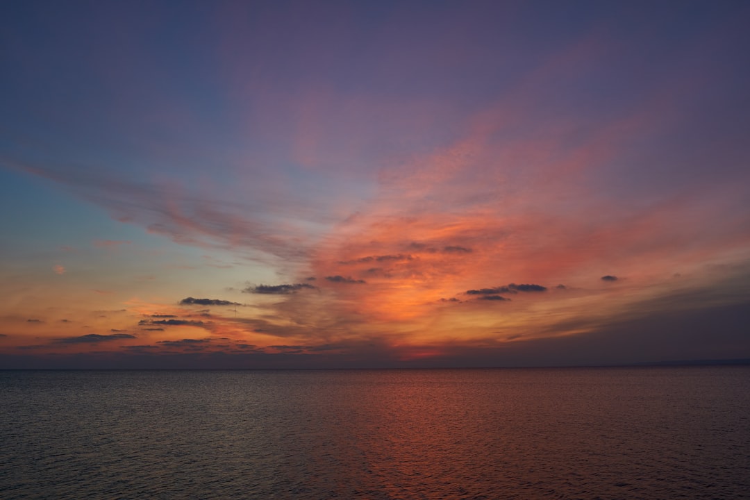 body of water under cloudy sky during sunset