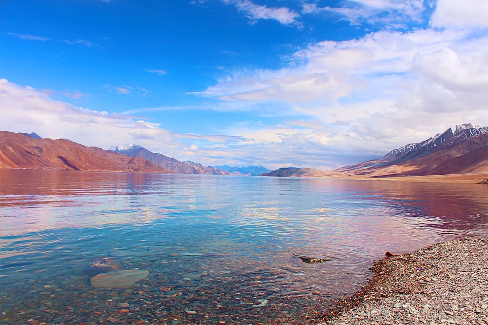 body of water near mountain under blue sky during daytime