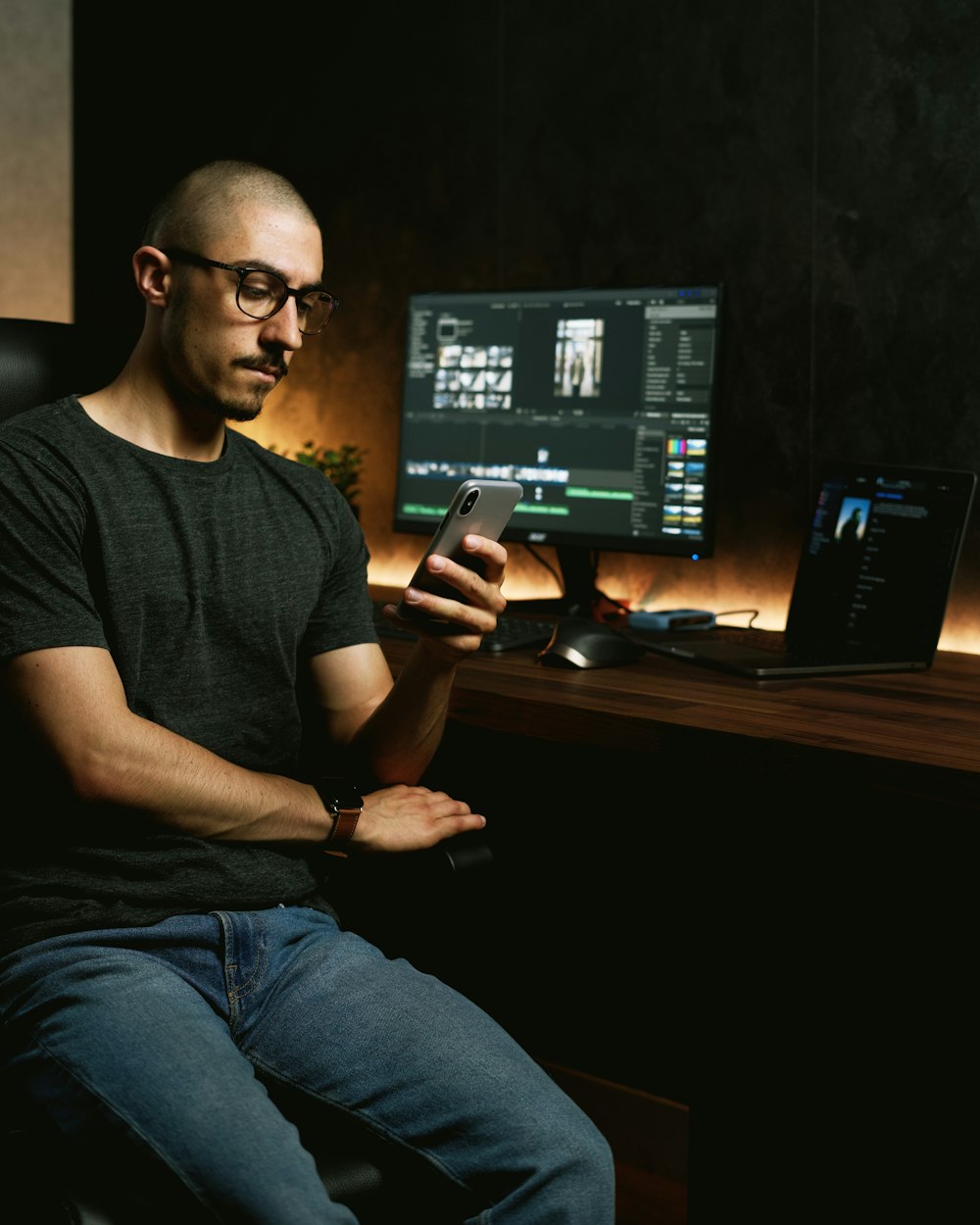 man in black crew neck t-shirt and blue denim jeans sitting on chair using computer