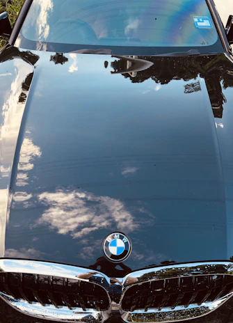Close-up of a glossy black sports car hood reflecting mountain scenery in Garmisch-Partenkirchen.