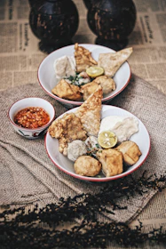 A colorful plate of kwek-kwek and fish balls topped with spicy sauce, styled with rustic street food aesthetics.