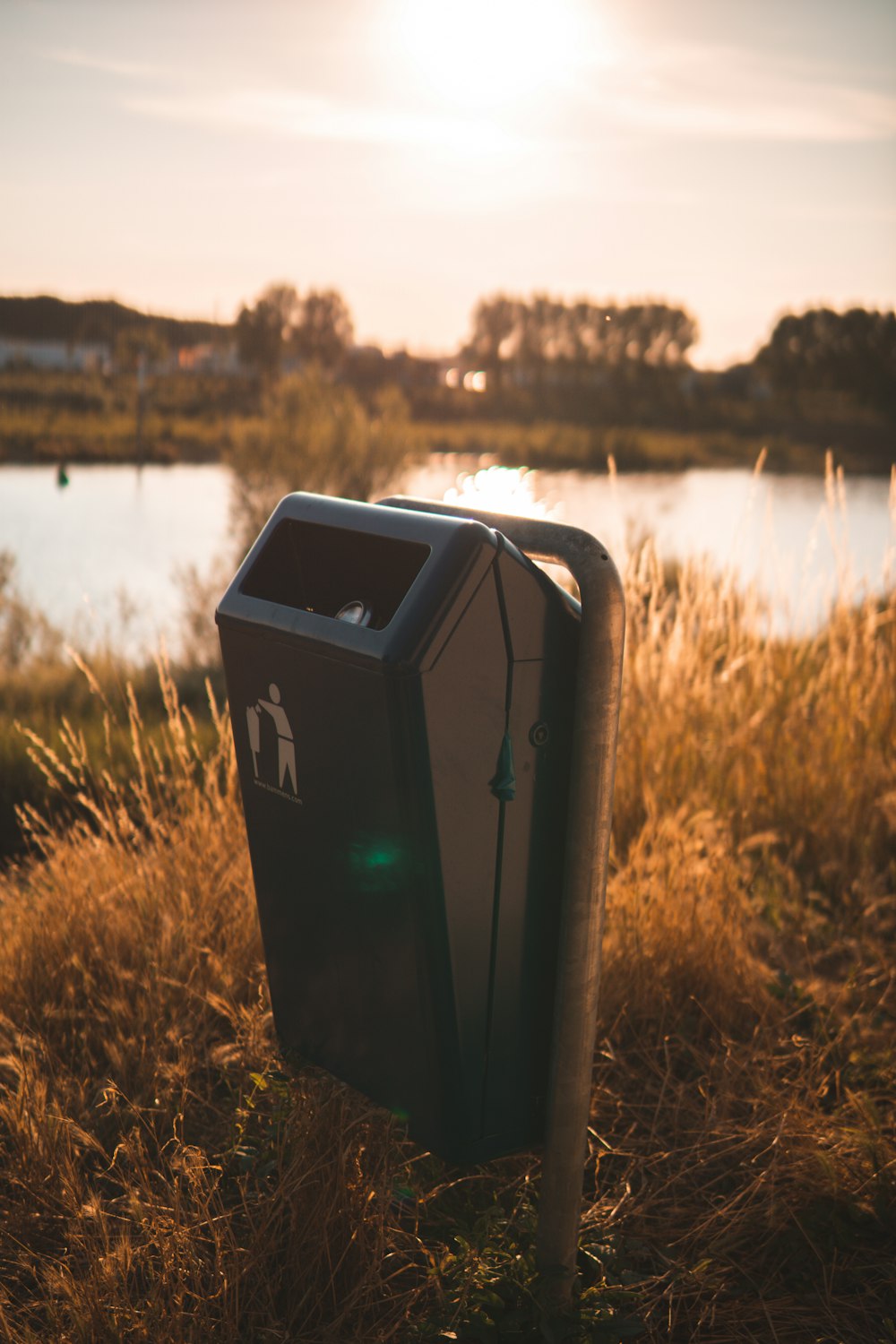 black trash bin near body of water during daytime