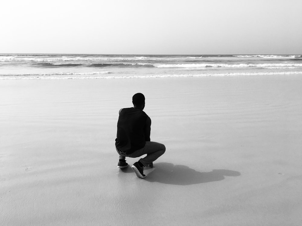 man in black hoodie sitting on beach