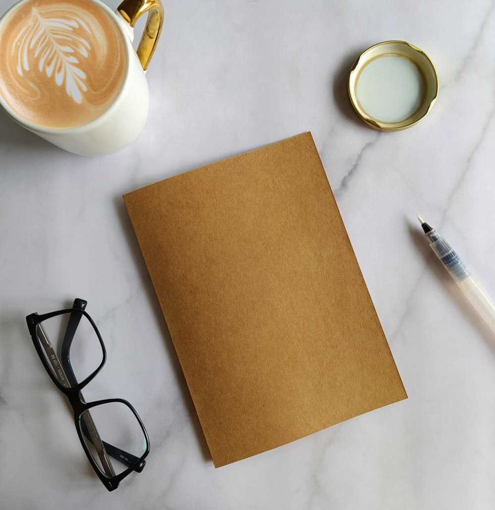 black framed eyeglasses beside white ceramic mug with coffee