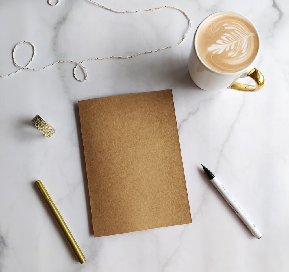 white ceramic mug beside silver bread knife and brown paper