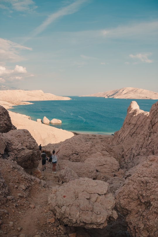 people standing on brown rock formation near body of water during daytime in Pag Croatia