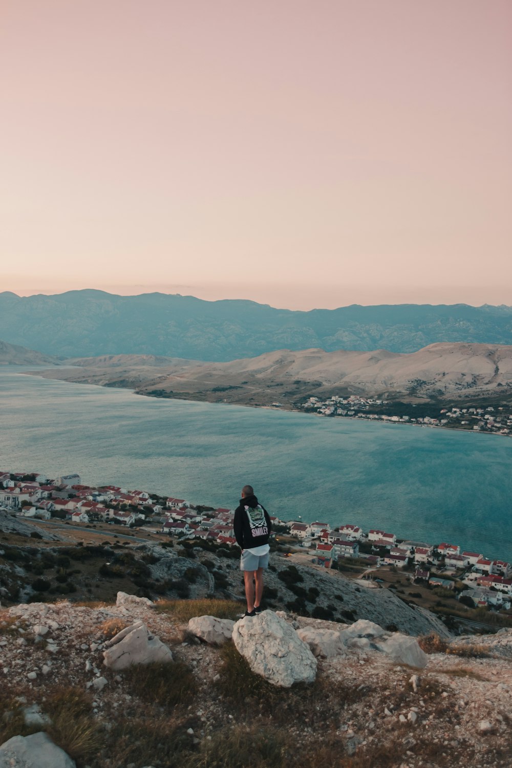 woman in black jacket standing on rock formation near body of water during daytime