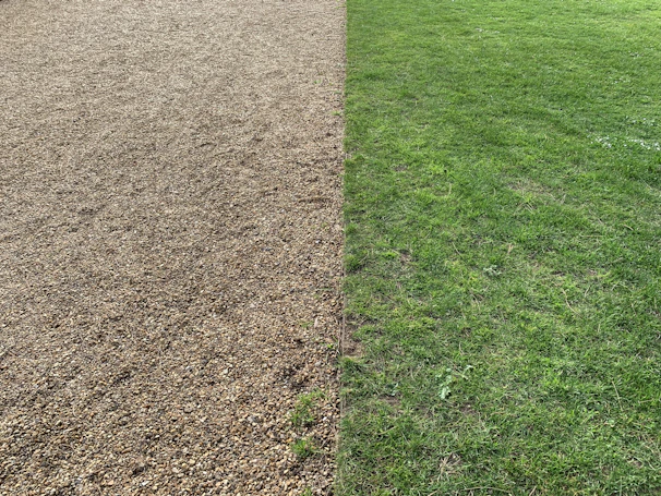 Grass edge separated by a clean plastic lawn strip from decorative gravel area.