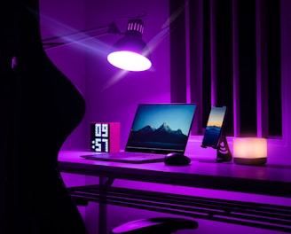 woman in black dress standing near black laptop computer on brown wooden desk