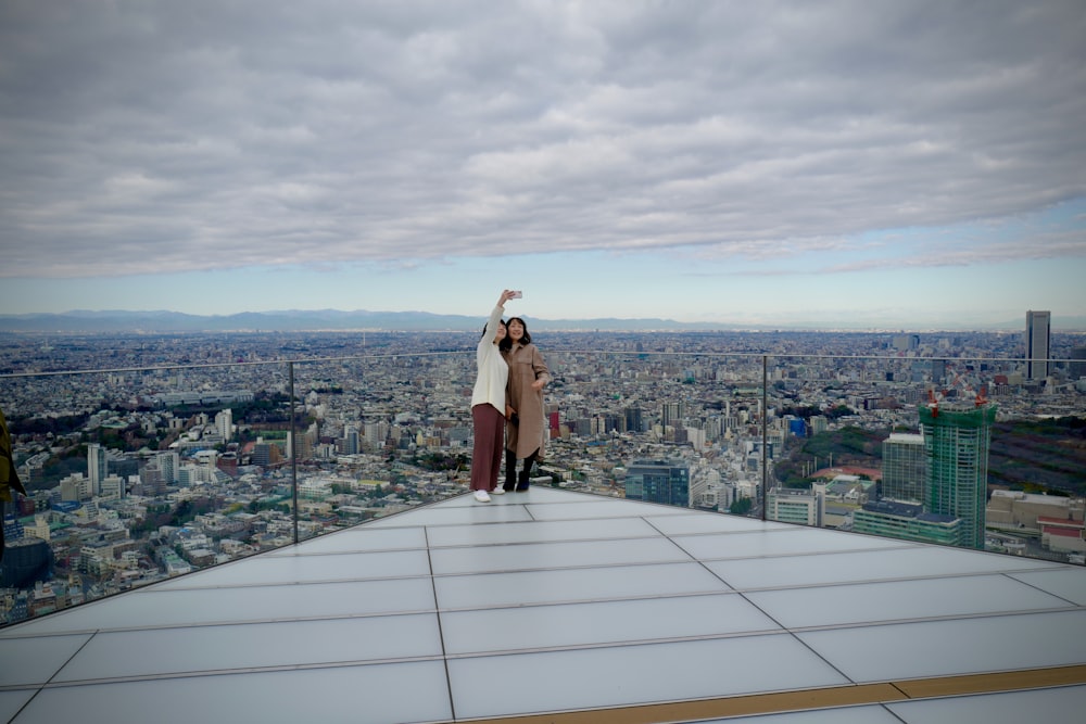 woman in brown coat standing on top of building during daytime