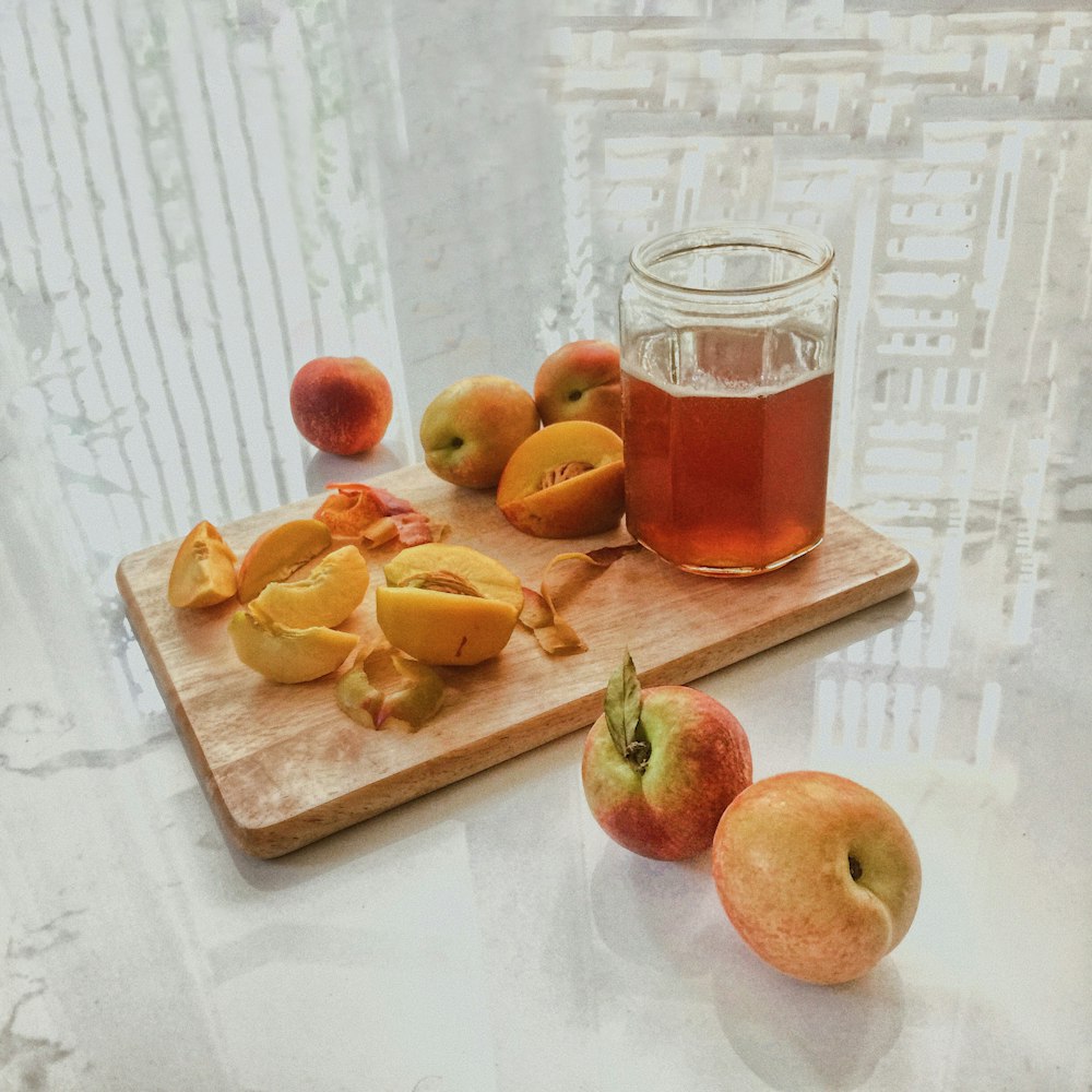 red apples beside clear glass mug with red liquid