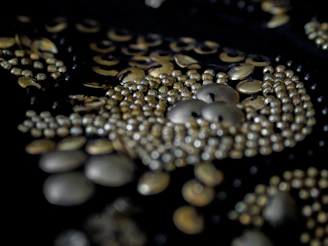Elegant metal buttons with intricate patterns displayed on a dark cloth.