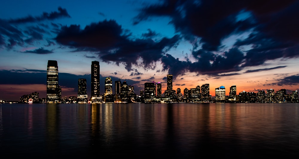 city skyline across body of water during night time