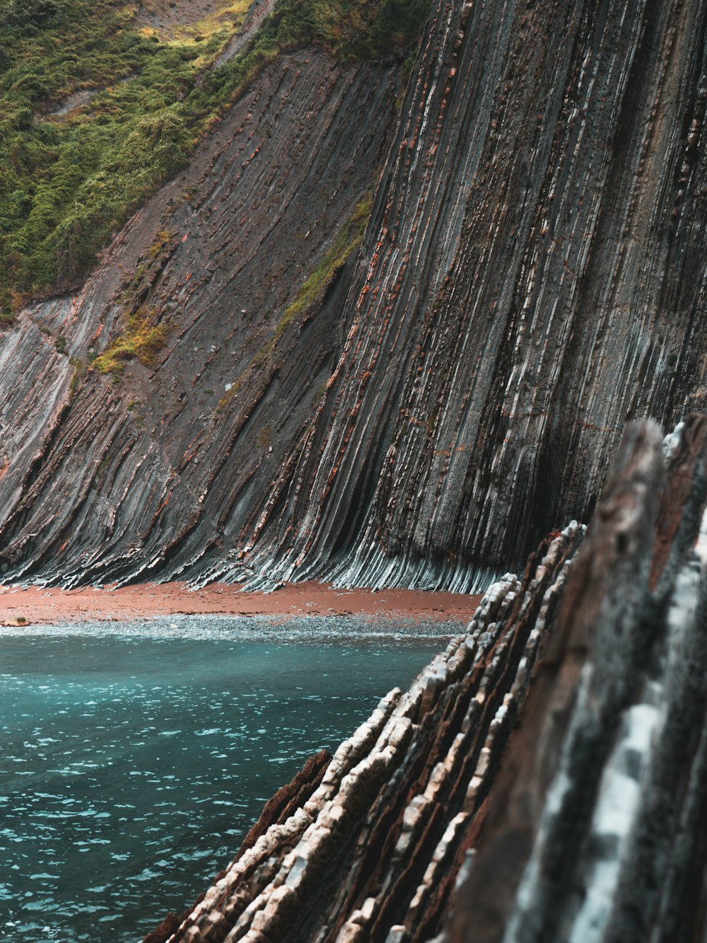 brown and green mountain beside body of water during daytime