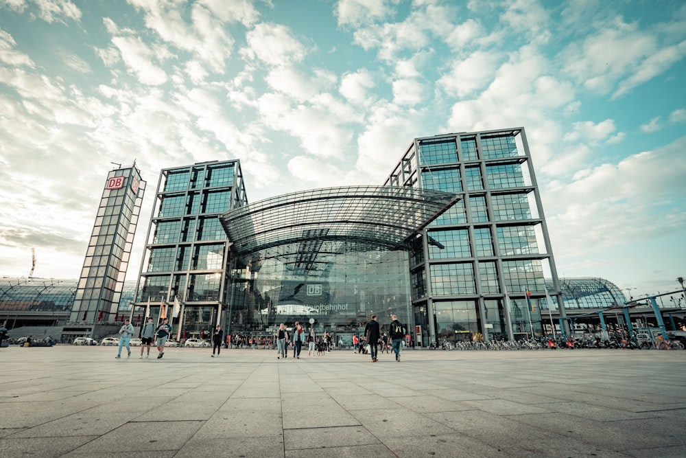 people walking on gray concrete floor near glass building during daytime