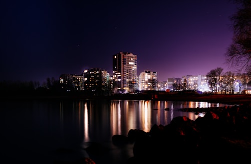 A serene nighttime cityscape with subtle, flowing colorful soundwave graphics overlay.