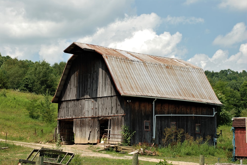 brown wooden barn under white clouds during daytime