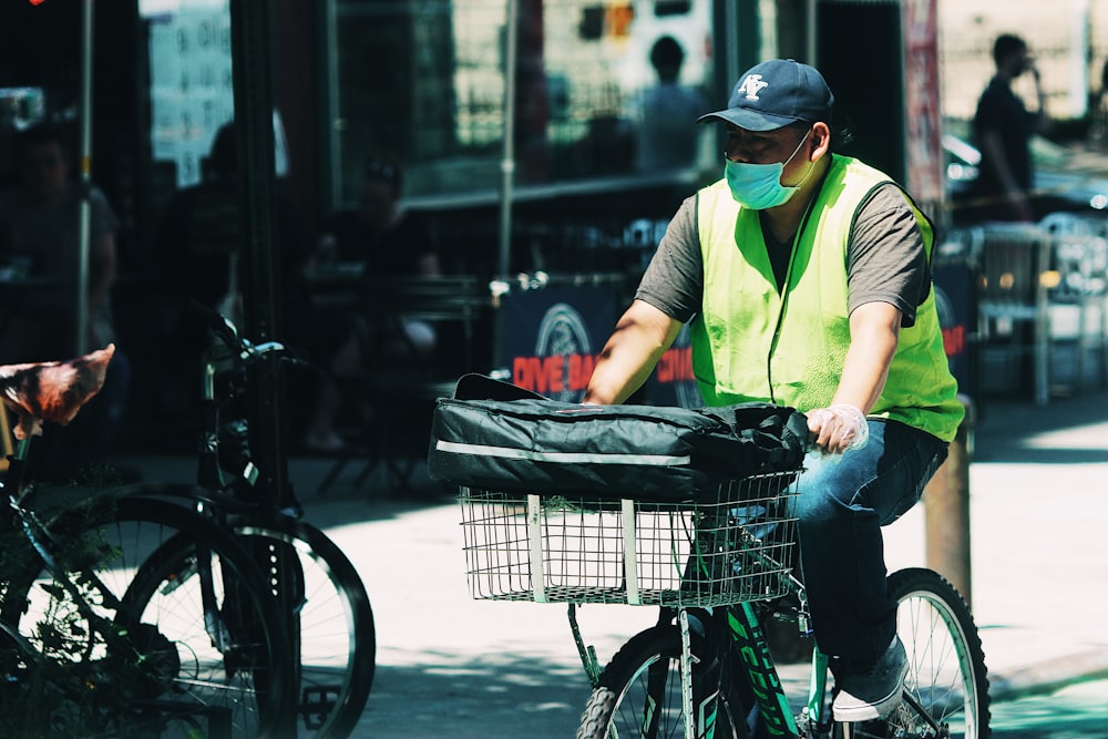 homem de camiseta verde e jeans azuis segurando uma cesta de frutas