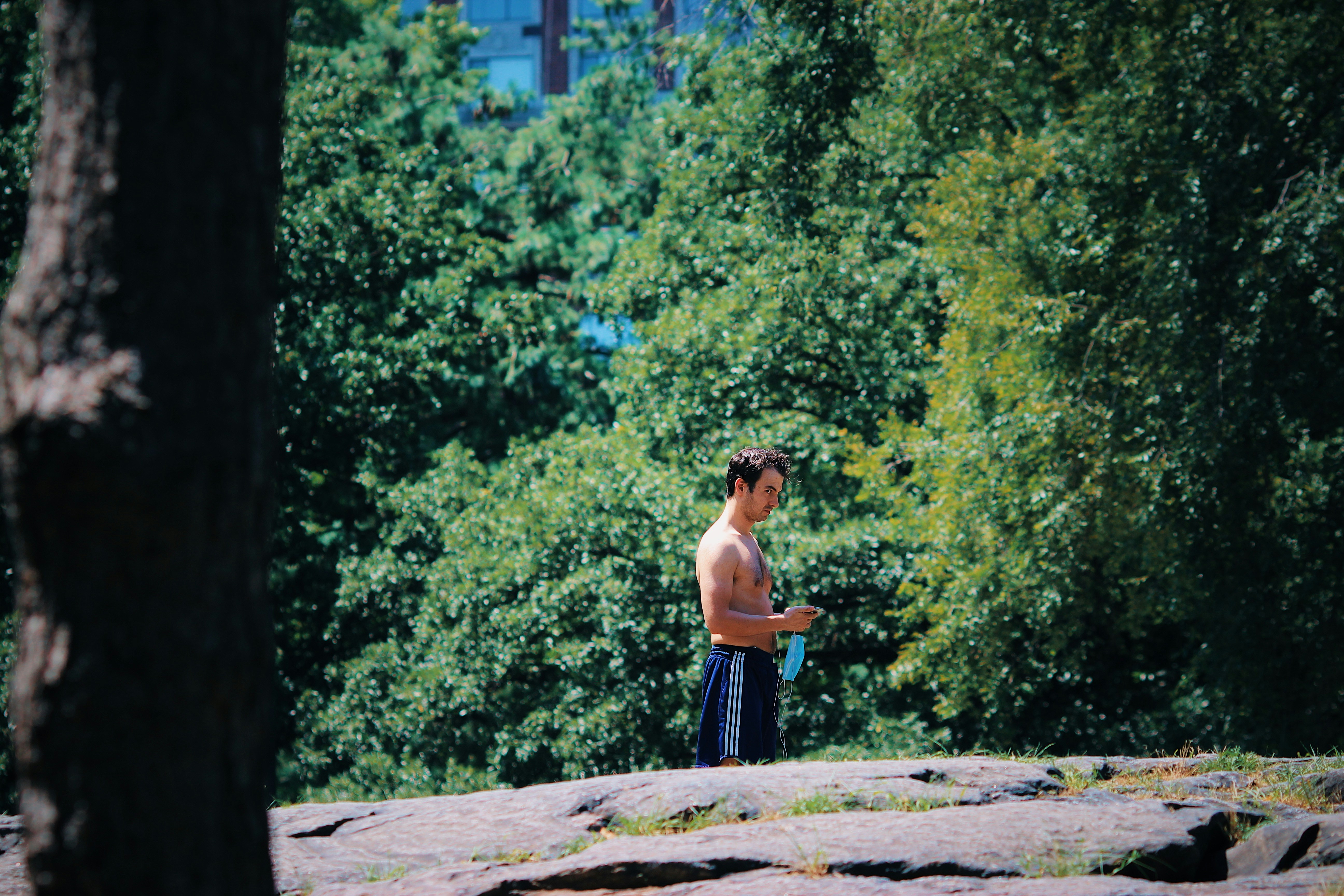 woman in black tank top and blue skirt standing on gray concrete pathway during daytime