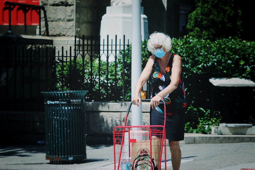 woman in blue tank top and red skirt holding red shopping cart