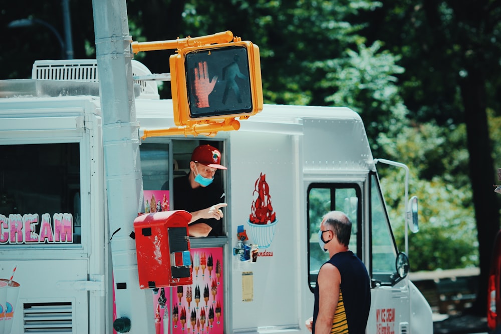 man in red and white santa hat standing beside white and red van during daytime