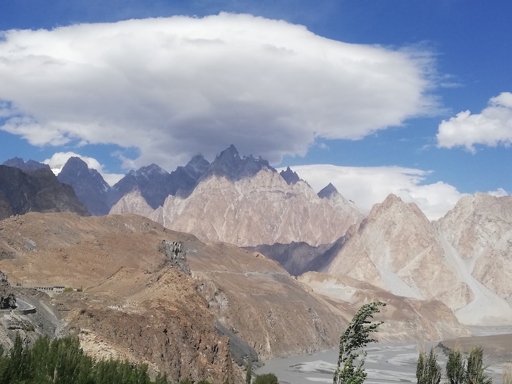 brown and white mountains under white clouds and blue sky during daytime