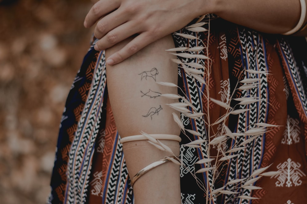 person with white and red floral tattoo on arm