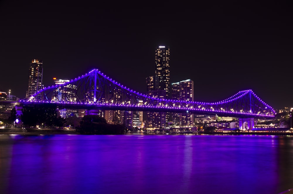 purple lighted bridge over water during night time