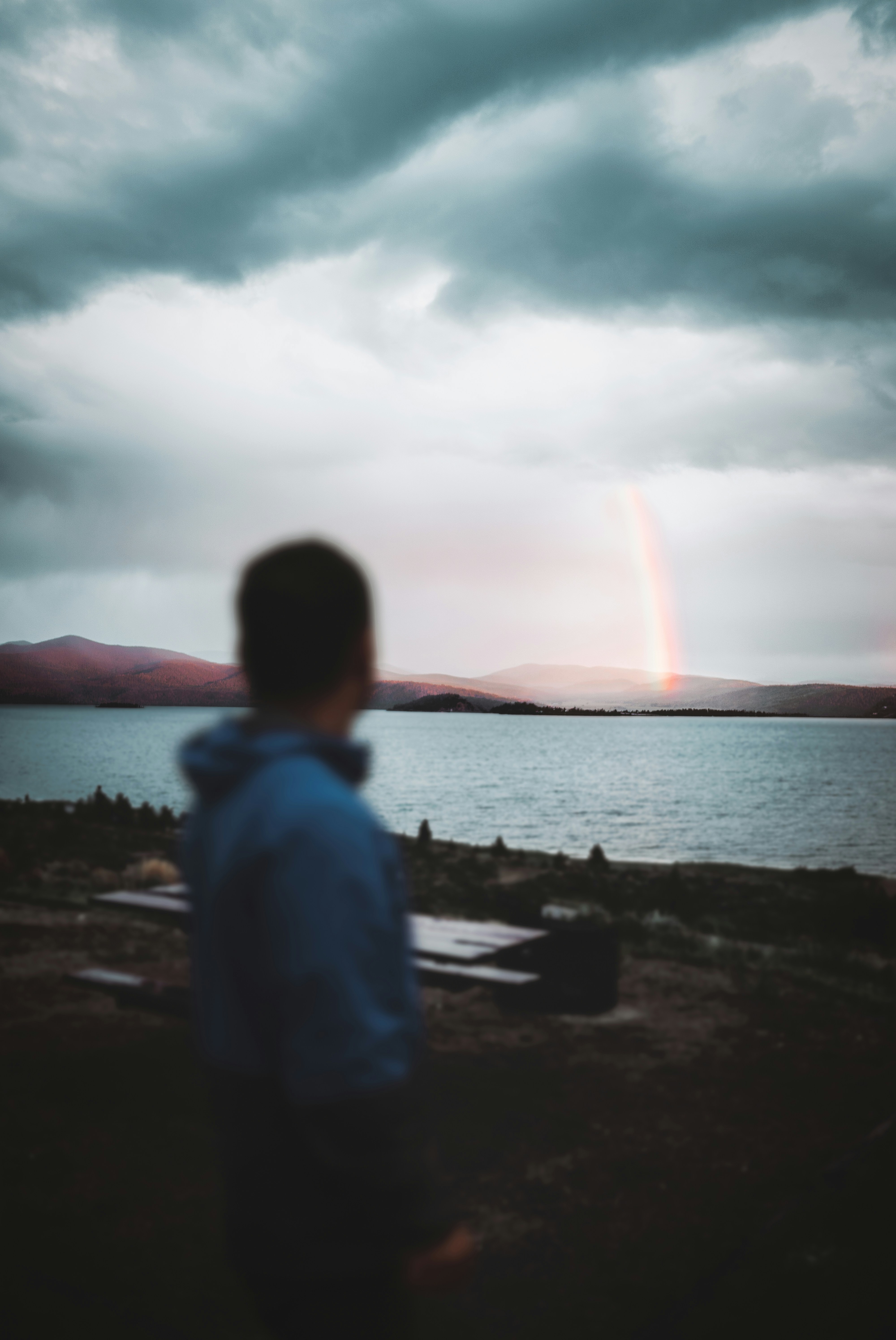 man in white shirt sitting on rock near body of water during daytime