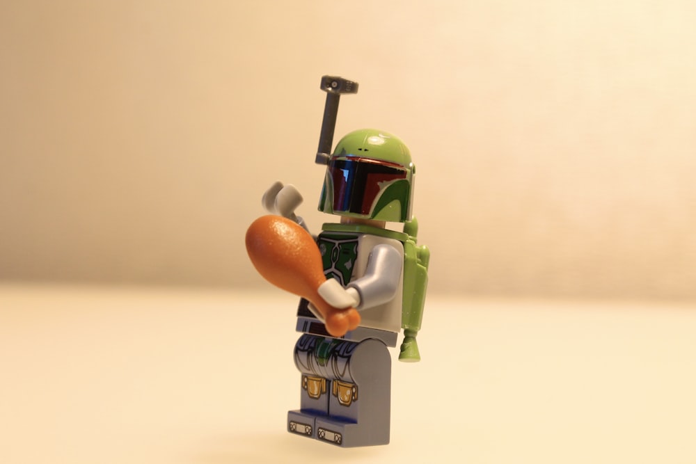a lego figure holding a carrot and a baseball bat