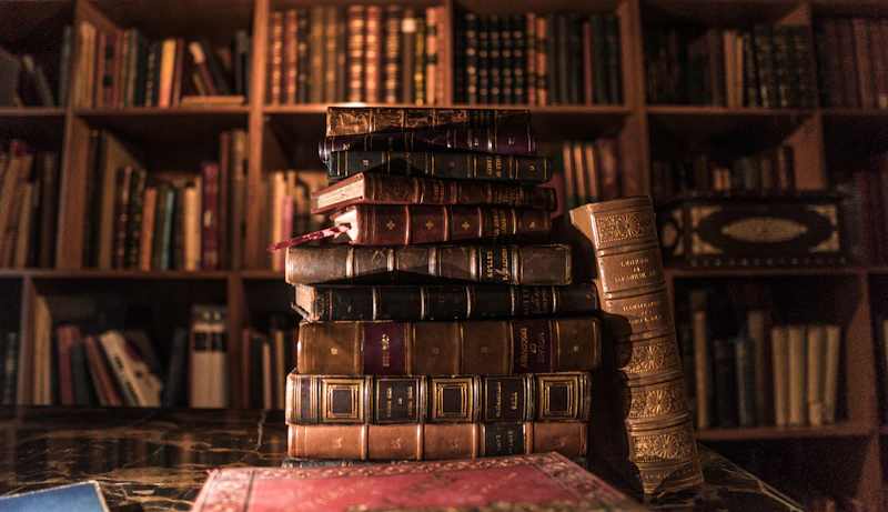 A tall stack of antique leather books in a dimly lit library