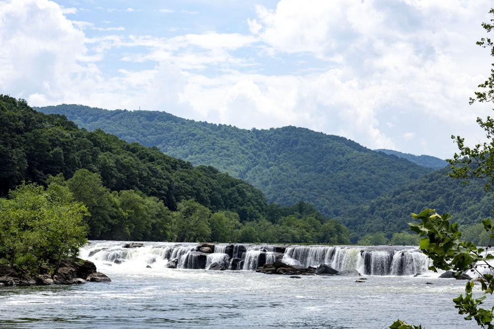 cascadas cerca de árboles verdes bajo nubes blancas y cielo azul durante el día