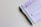A black and blue pen placed alongside a purple document that appears to contain instructions and a section for signatures. The pen is a retractable ballpoint style with a visible ink chamber and a textured grip. The document includes bold text, bullet points, and a signature area marked with an X.