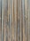 A collection of vertically arranged steel rebar rods displaying a range of rusted and weathered textures. The bars are closely packed and exhibit a pattern of parallel lines and grooves.