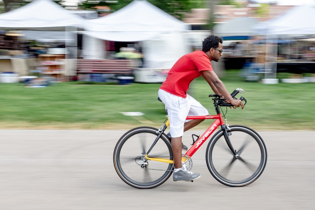man in red shirt riding on bicycle during daytime