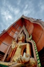 gold buddha statue under cloudy sky during daytime