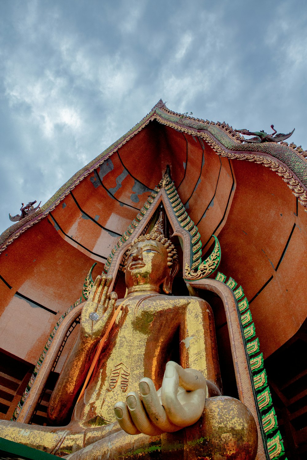 Statue de Bouddha en or sous un ciel nuageux pendant la journée