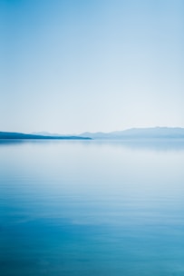 blue body of water under white sky during daytime